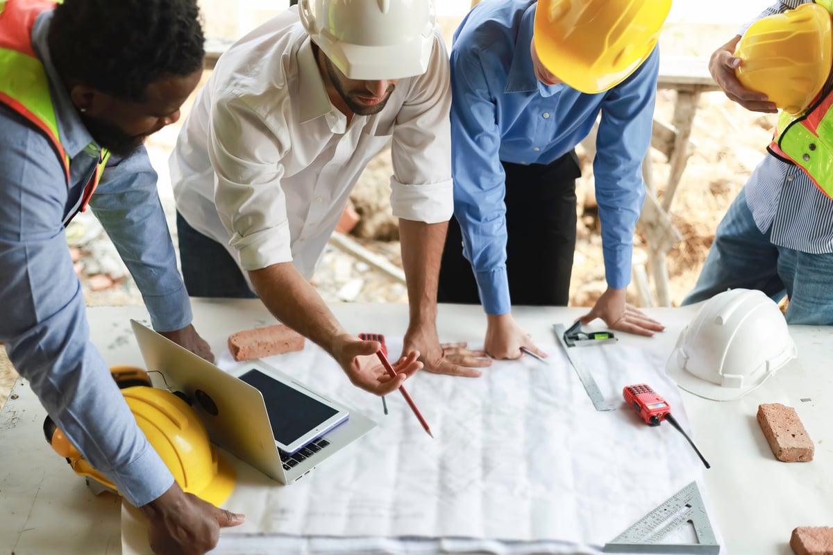 Professional engineers and construction team reviewing project plans at an active construction site