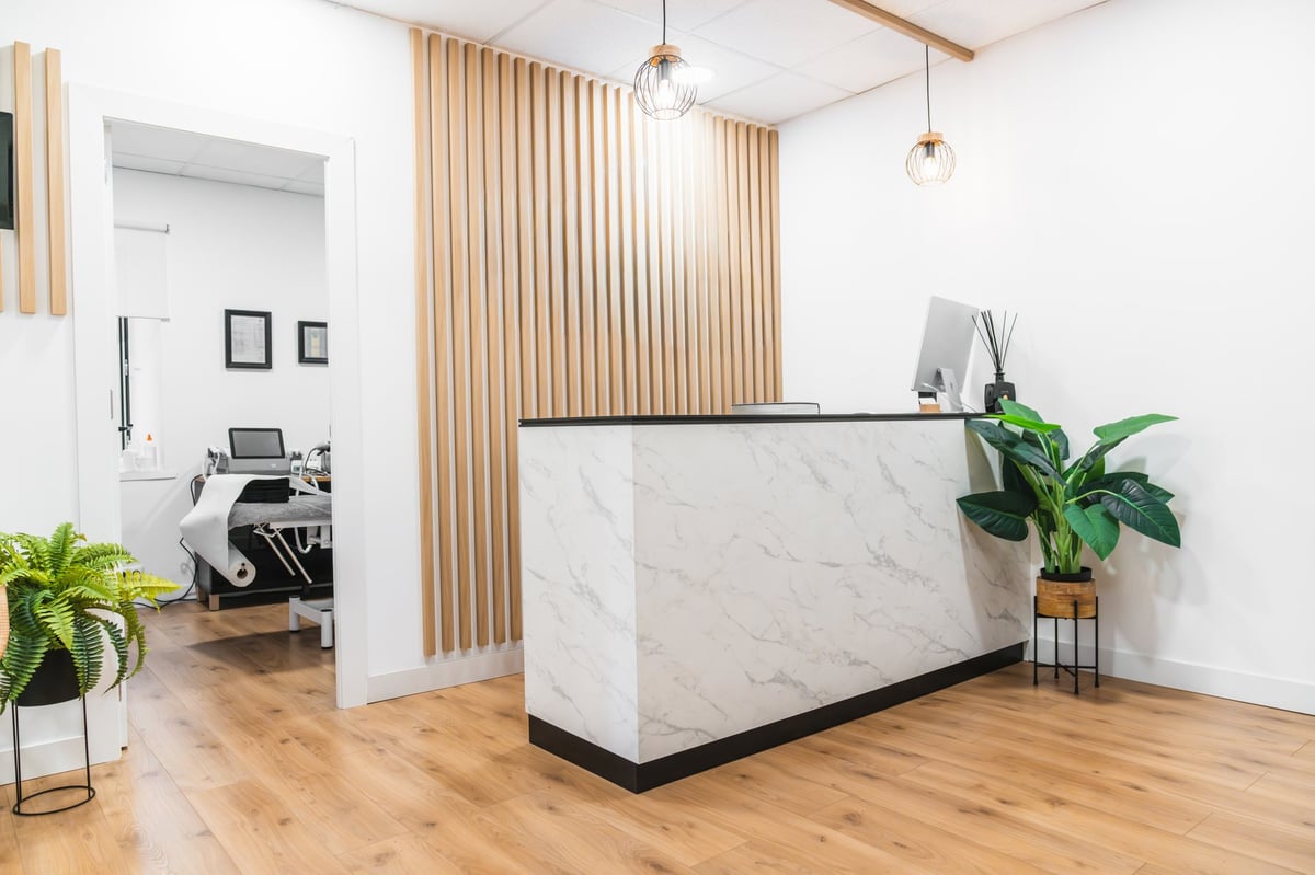 Clean modern healthcare clinic reception with marble counter and natural light
